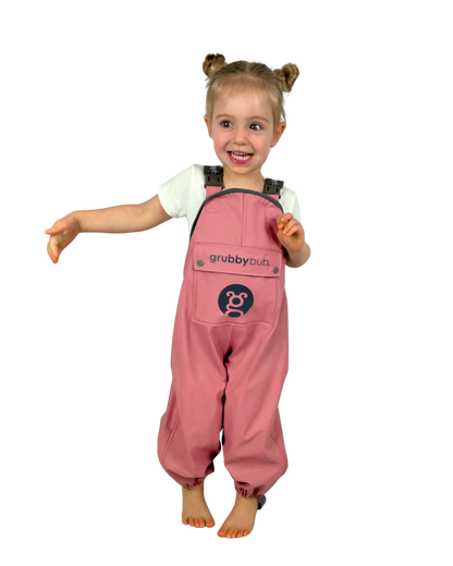 Child wearing pink 'grubbybubs' waterproof rain overalls on a white background