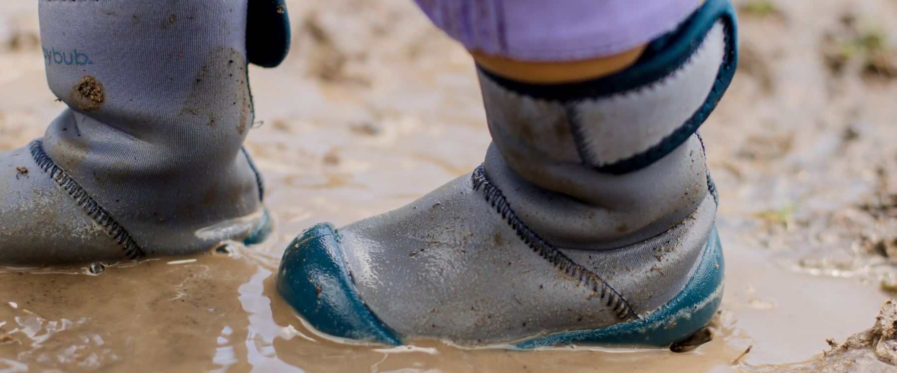Toddler in Wee Wellies soft sole wellies in muddy puddle, lightweight flexible wellies for outdoor play and forest school